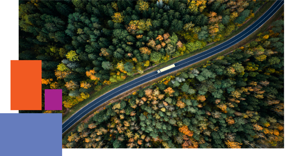 A truck driving down a motorway through trees 