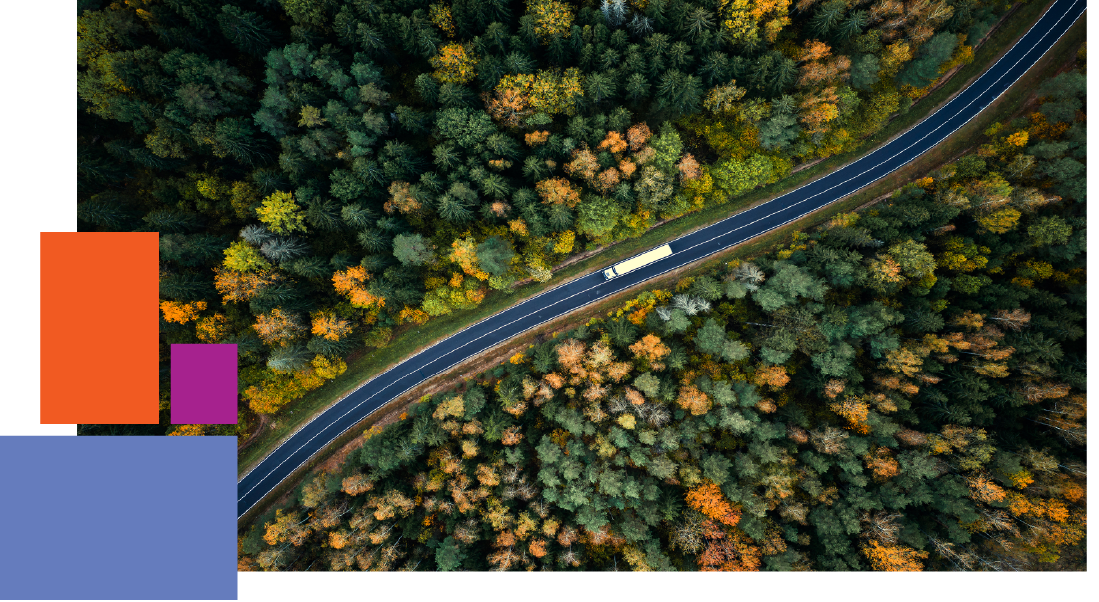 A truck driving down a motorway through trees 