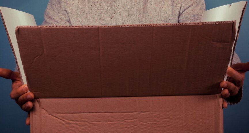 A surprised young man looking inside an opened cardboard box